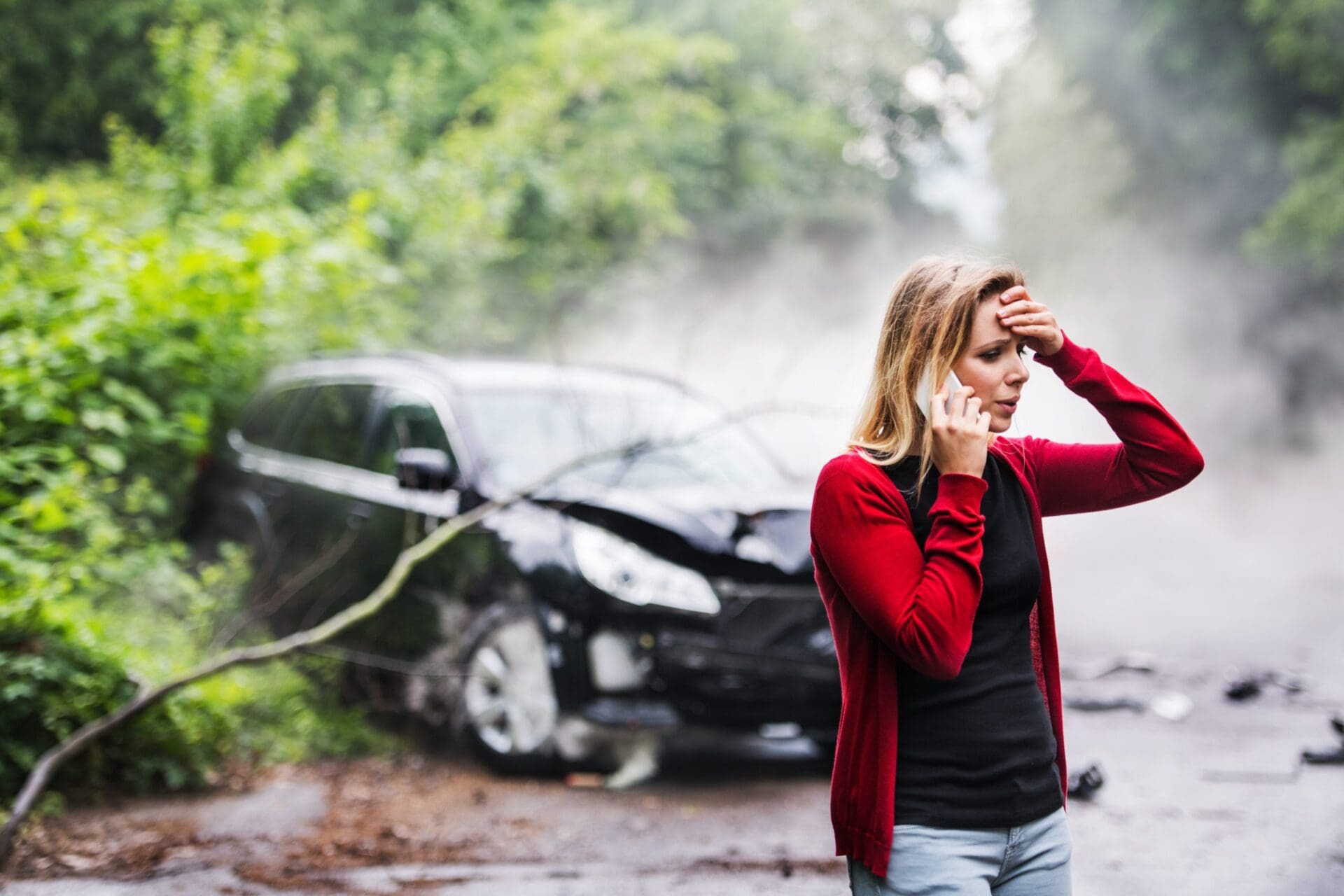 A young woman with smartphone by the damaged car after a car accident, making a phone call. car accident